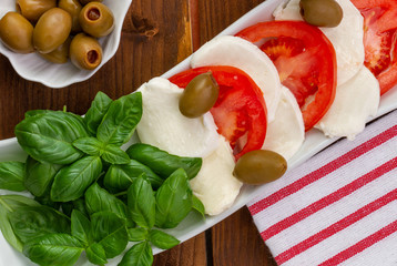 Swieza mozzarella z plastrarmi pomidora i listkami bazyli. Rustykalna kuchnia. Wegetarianskie danie. Vege salatka. © ff25