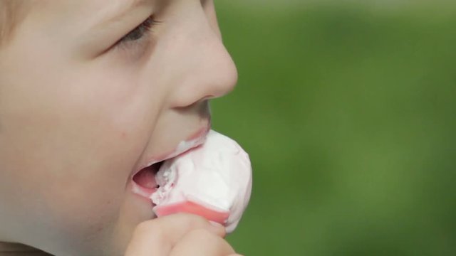 Ice cream bites a boy close up,Pink ice cream bites a boy close-up on a green background in the summer