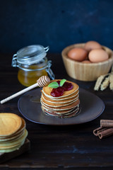 delicious pancakes with jam and mint on a dark wooden table