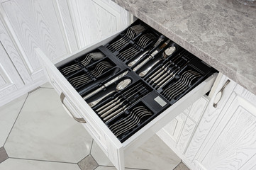 drawer with silver cutlery in modern white kitchen