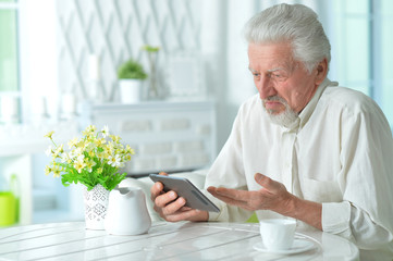 Portrait of thoughtful senior man using tablet