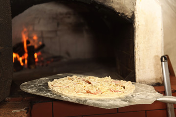 Putting pizza into oven in restaurant kitchen