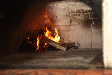 Oven with burning firewood in restaurant kitchen