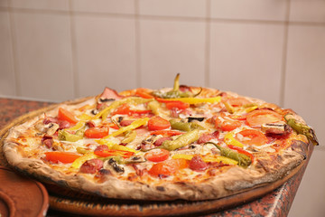 Wooden board with delicious pizza on table in restaurant. Fresh from oven