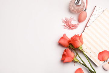 Flat lay composition with coral roses, notebooks and perfume bottle on white background. Space for...