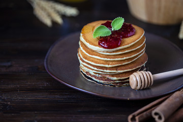 delicious pancakes with jam and mint on a dark wooden table