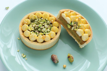 Modern tarts with tropical flavor decorated with pistachio on green plate