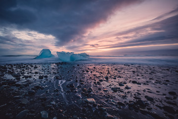 Beautiful sunset over famous Diamond beach in Iceland. This black sand lava beach is full of many giant ice chunks, placed near glacier lagoon Jökulsárlón in southeast Iceland.