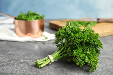 Fresh green parsley on grey table against color background, space for text