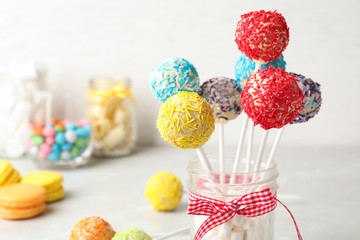 Fototapeta na wymiar Yummy bright cake pops in glass jar full of marshmallows on table. Space for text