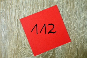 Fototapeta na wymiar Emergency number 112 written on small red sticker