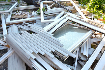 Many different construction debris from old plastic window frames of white color with glass.  The...