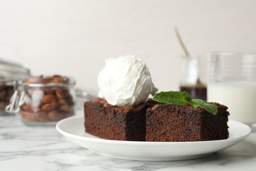 Plate with fresh brownies and ice-cream on table. Delicious chocolate pie