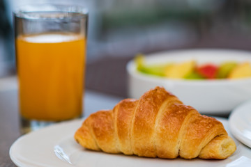 Continental breakfast with fresh croissant, orange juice and fruits, selective focus