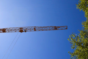 Construction crane on a blue sky background. Building on a sunny day. Construction crane yellow color.