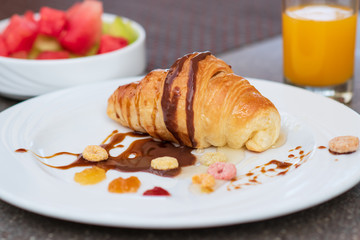 Continental breakfast with fresh croissant, orange juice and fruits, selective focus