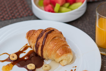 Continental breakfast with fresh croissant, orange juice and fruits, selective focus