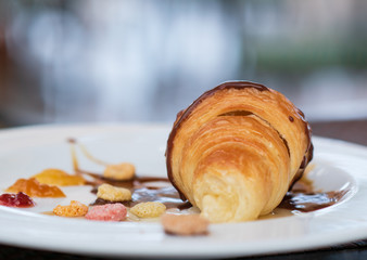 fresh croissant topped with honey, chocolate and jam on a plate. selective focus