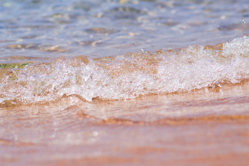 Fototapeta na wymiar Closeup photo of sea waves rolling on the sandy sea beach. bokeh background.