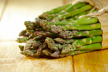 Fresh green asparagus on yellow wooden table 