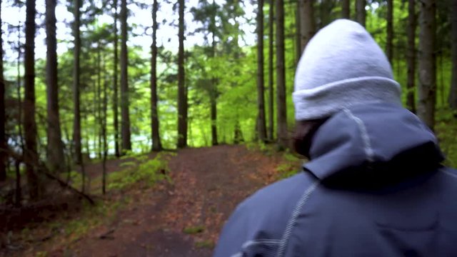 Man on Walk in Nature. Walking in the mountain deep forest. Boy with a hat walking in the woods. Gimbal Head Tracking Shot. Hikers enjoying the awesome view in the forest