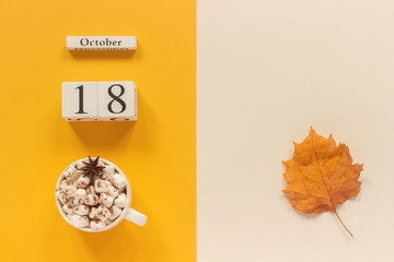 Autumn composition. Wooden calendar October 18, cup of cocoa with marshmallows and yellow autumn leaves on yellow beige background. Top view Flat lay Mockup Concept Hello September