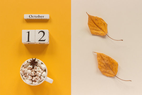 Autumn composition. Wooden calendar October 12, cup of cocoa with marshmallows and yellow autumn leaves on yellow beige background. Top view Flat lay Mockup Concept Hello September