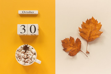 Autumn composition. Wooden calendar October 30, cup of cocoa with marshmallows and yellow autumn leaves on yellow beige background. Top view Flat lay Mockup Concept Hello September