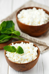 fresh homemade cottage cheese in a wood bowl with mint leaves, on white background. top view