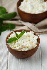fresh homemade cottage cheese in a wood bowl with mint leaves, on white background. top view