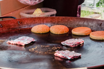 street food, hamburgers and meat patties in a large frying pan