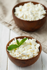 fresh homemade cottage cheese in a wood bowl with mint leaves, on white background. top view