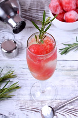 Sparkling cocktail with watermelon balls and rosemary in a champagne glass on white table