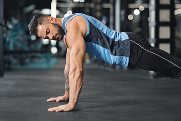 Fototapeta premium Sporty young man doing pushups in gym