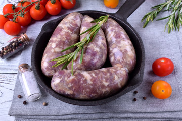 Raw meat sausages in a natural shell in a cast iron pan prepared for grilling