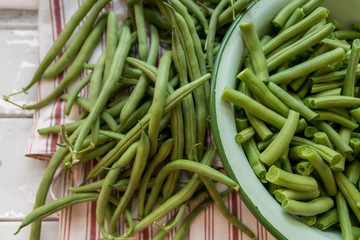 Freshly picked organic green beans in a vintage enamel bowl on a red stripe linen table cloth