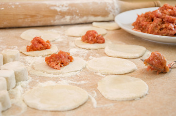 concept of cooking dumplings: dough, minced meat, flour, rolling pin on the kitchen table.