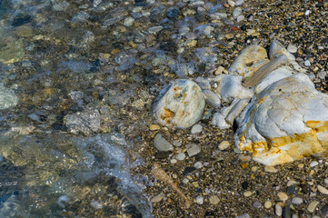 pebble stones on the sea beach, the rolling waves of the sea with foam