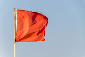 red flag in the wind against blue sky