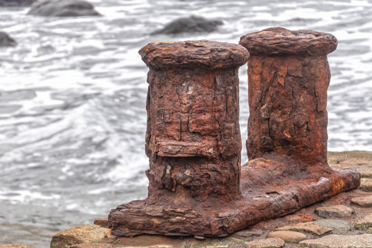 Old, rusty iron bollard in the harbor