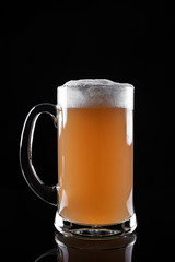 Mug of foamy beer isolated on dark background