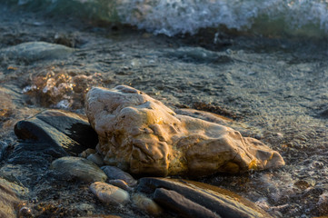 pebble stones on the sea beach, the rolling waves of the sea with foam
