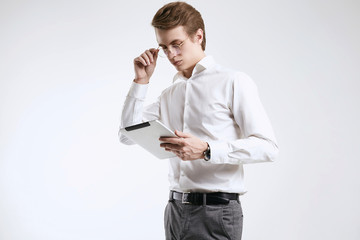 Confident young businessman in shirt working on digital tablet