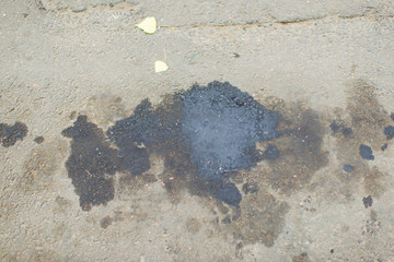 Oil stains on the asphalt. Dirty surface of grey asphalt road. Black oil stains on the sidewalk.