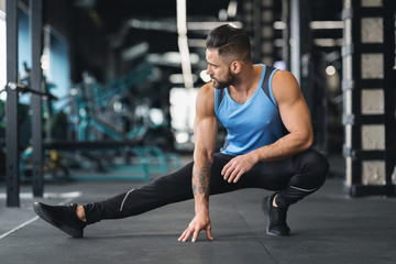 Fototapeta na wymiar Sporty man at gym doing stretching exercises for legs