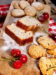 Oatmeal cookies and cherry on kitchen cutting board gingham checkered cotton fabric on table in village style for picnic. New dishes in expensive cafe. Festive table decoration.