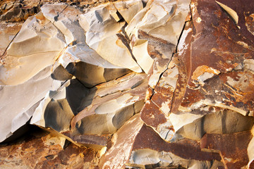 Stone breaks in the rays of sunset. Red and orange stone texture