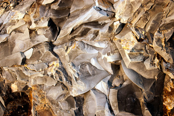 Stone breaks in the rays of sunset. Red and orange stone texture
