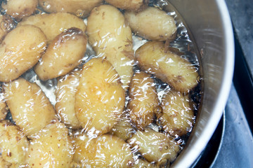 Jersey royal potatoes cooking in boiling water in a large saucepan