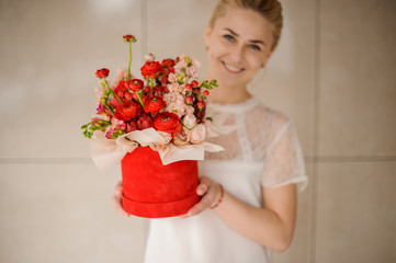 Girl holding a red velvet box of scarlet and pink flowers